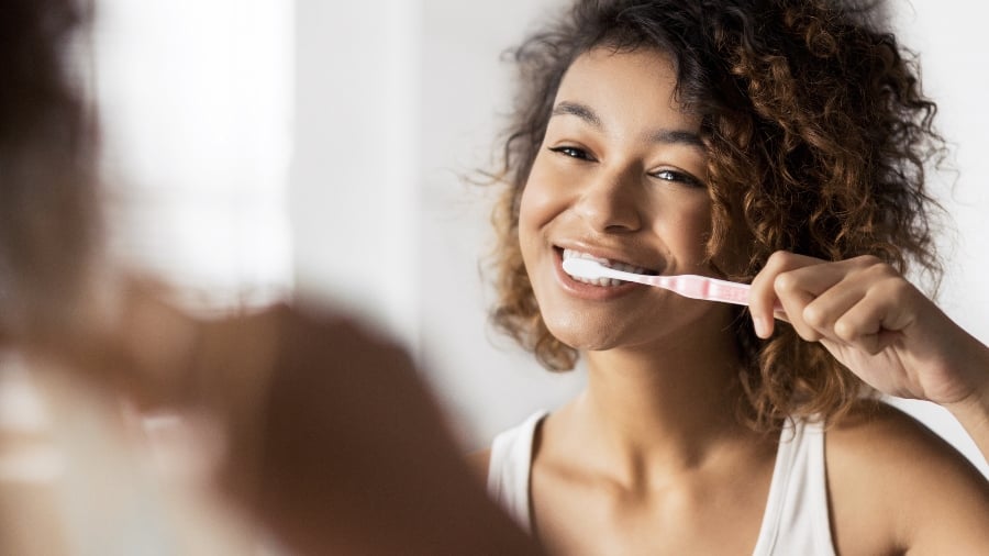 Woman brushing her teeth with non-vegan toothpaste