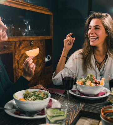 Two smiling women enjoy a vegan meal during Veganuary