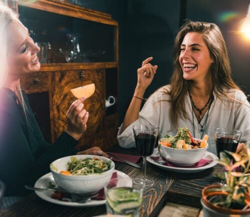 Two smiling women enjoy a vegan meal during Veganuary
