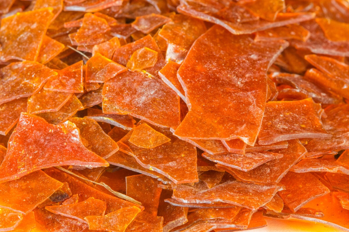 A pile of orange flakes of shellac, a non-vegan ingredient used in nail polish and candy