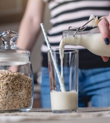 Woman pours a glass of oat milk