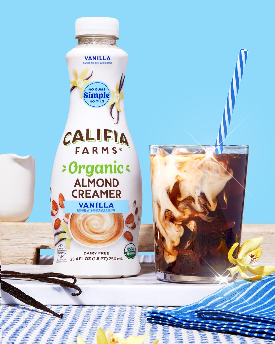 Photo shows a bottle of Califia Farms new plant-based organic Almond Creamer next to a glass of iced coffee against a pale blue background
