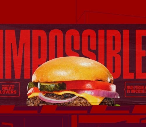 Photo shows a burger made with an Impossible Foods patty in a dark red background with the company logo on it - part of a new brand-wide redesign