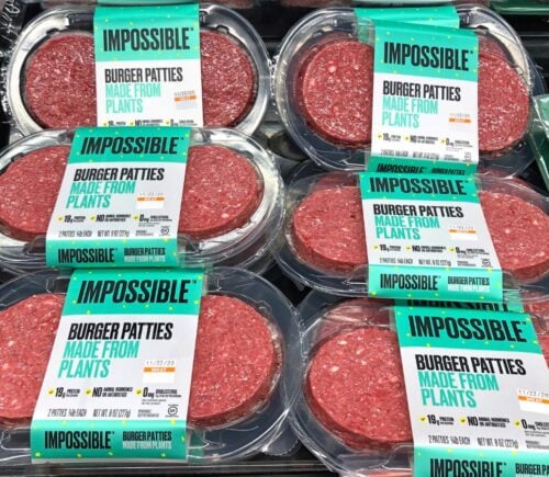 Photo shows several packages of Impossible Meat patties on display alongside animal-based proteins