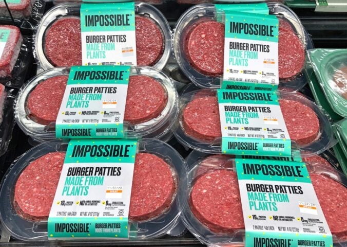 Photo shows several packages of Impossible Meat patties on display alongside animal-based proteins
