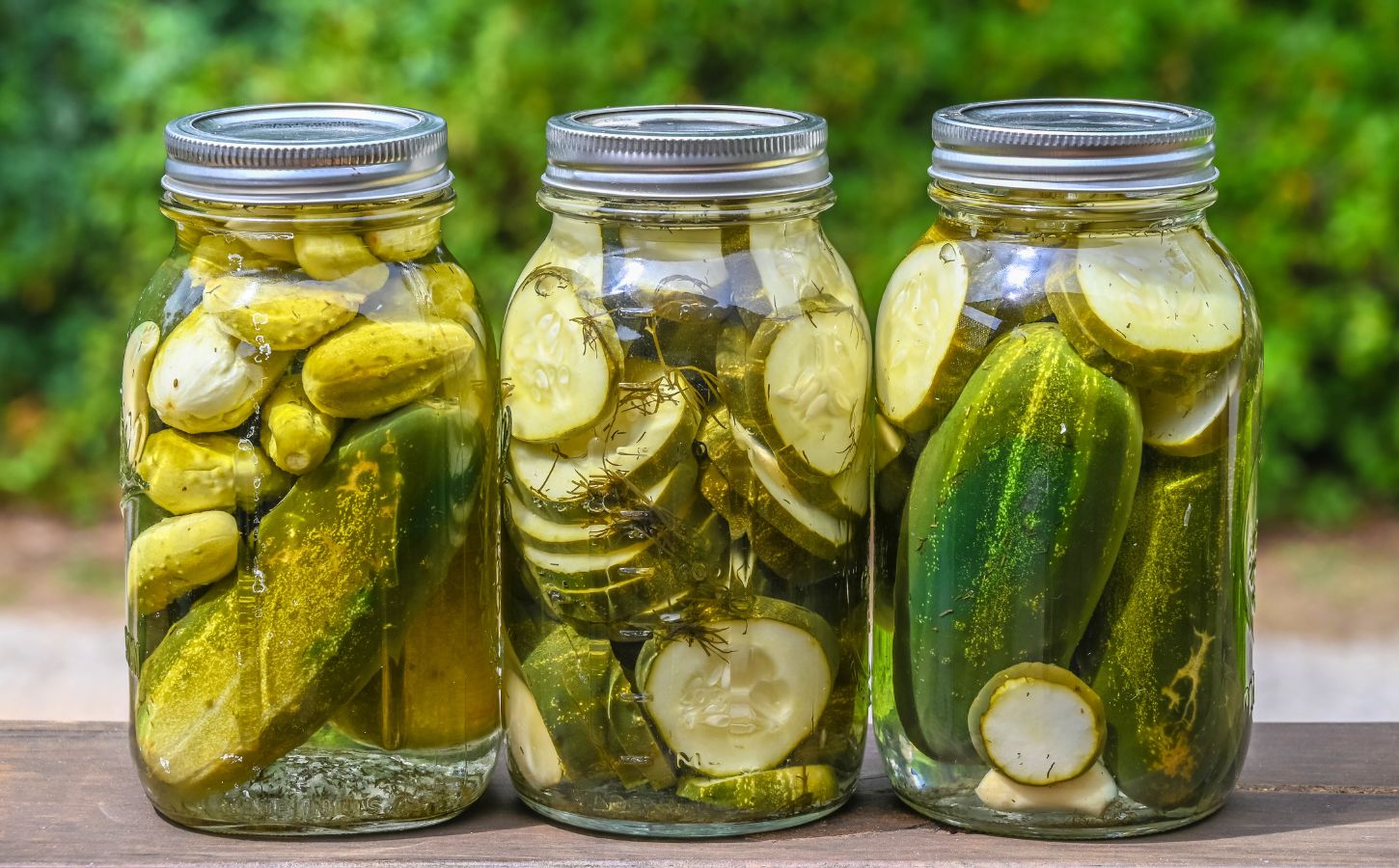 Three pickle jars filled with a selection of pickles