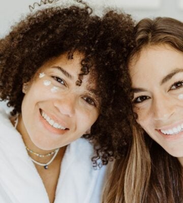 Two women with patches of natural skincare on their faces smiling at the camera