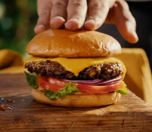 A still from dairy-free company Daiya's advert featuring a real beef burger with vegan cheese