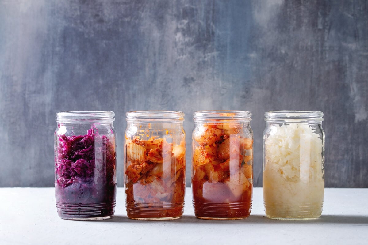 Photo shows a row of jars containing pickles and fermented vegetables, each of a different variety