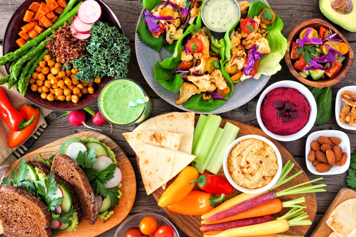 Photo shows a colorful, plant-based lunchtime spread including vegetable bowls, fresh salad, and pulses