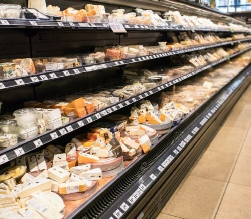 Photo shows the dairy aisle of a supermarket complete with several different varieties of cheese