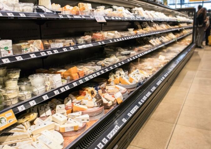 Photo shows the dairy aisle of a supermarket complete with several different varieties of cheese