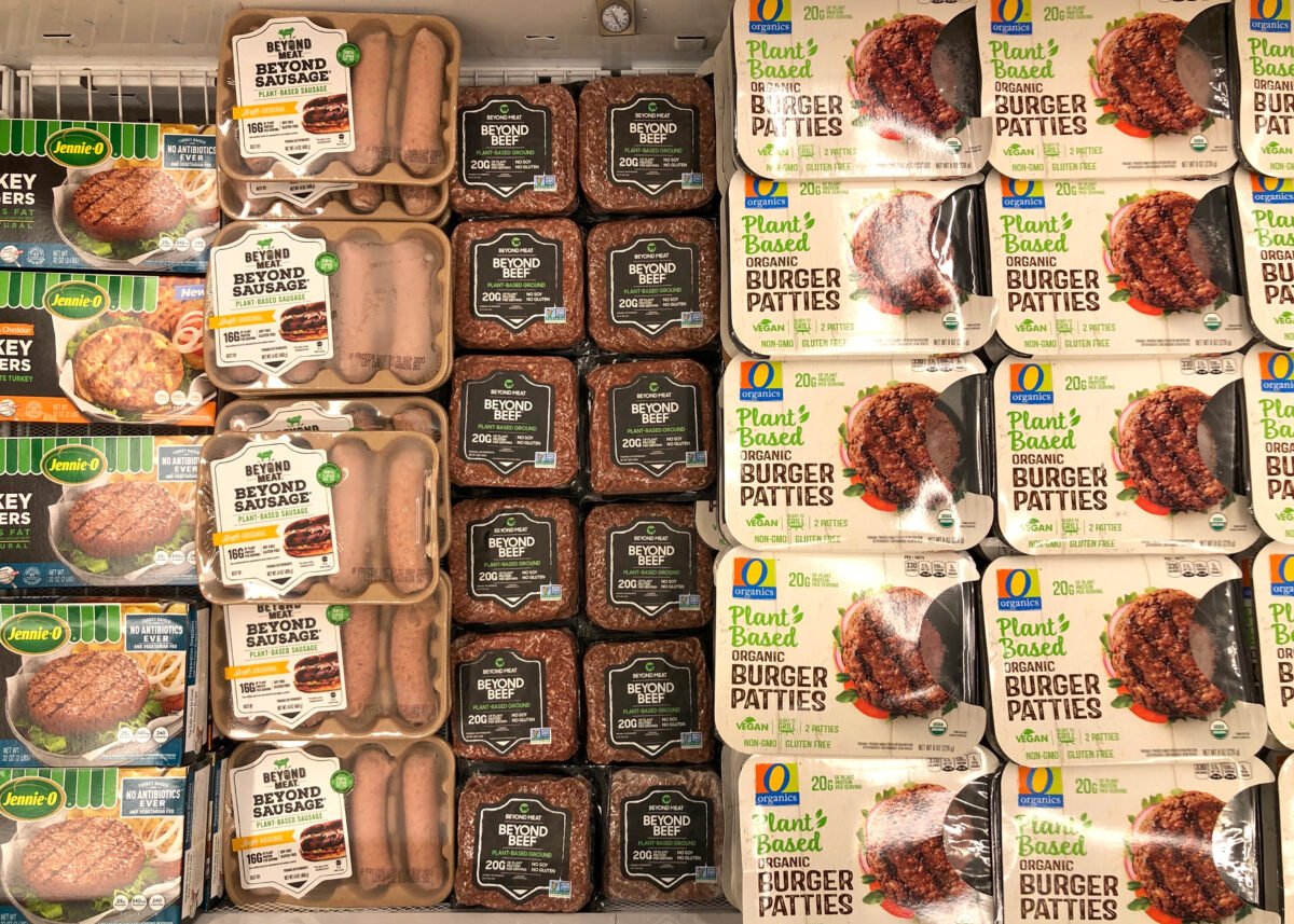Photo shows stacks of plant-based meat products in refrigerated supermarket shelves