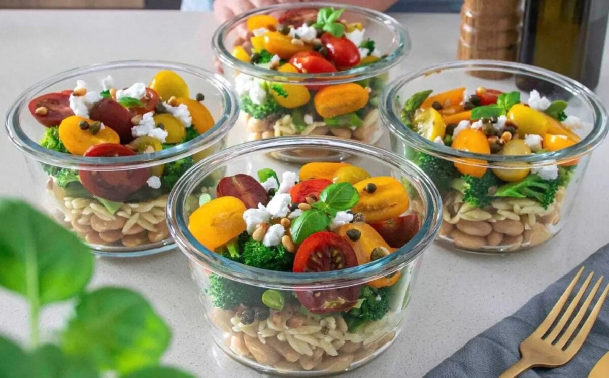 Photo shows four colorful bowls of orzo, bean, and pesto salad on a table