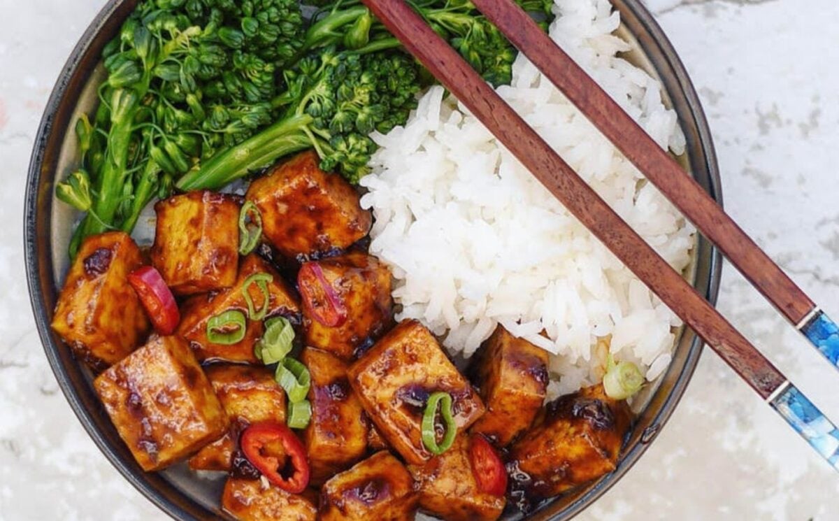 Photo shows a tofu and broccoli bowl served with rice and chopsticks