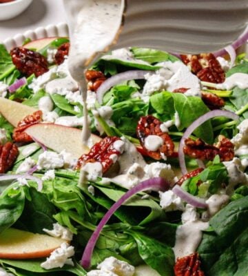 A spinach argula salad with candies pecans and apples