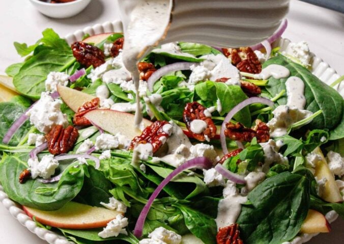 A spinach argula salad with candies pecans and apples