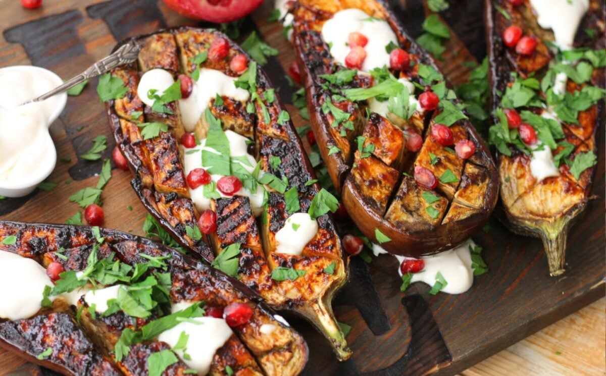 Photo shows four seasoned, cooked, and carefully topped miso aubergine steaks prepared to a vegan recipe