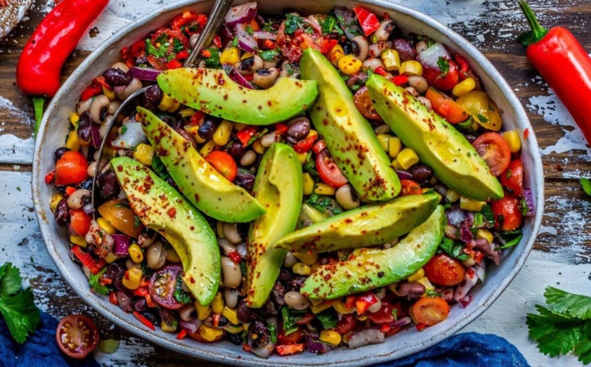 A Mexican bean salad with avocado on the top 