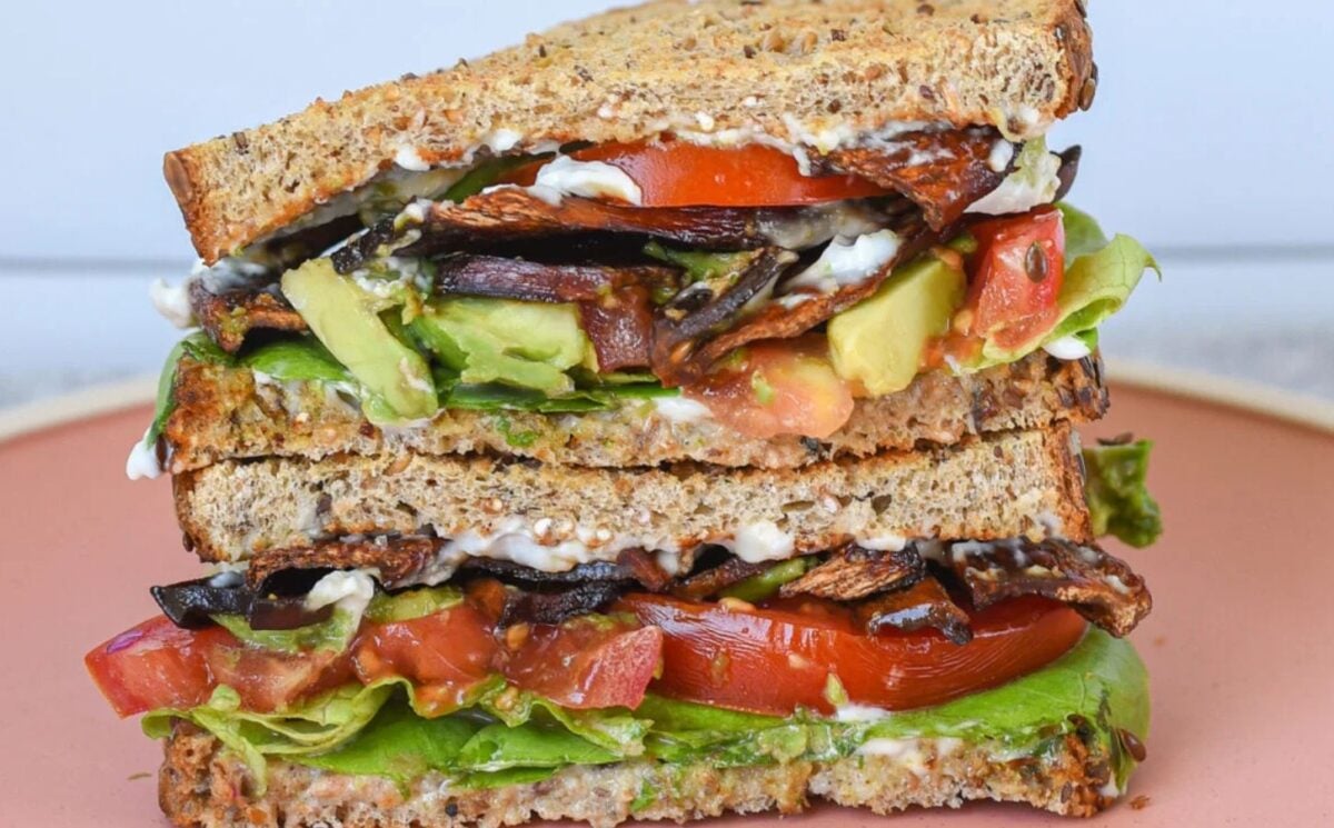 Photo shows an oyster mushroom-based BLT-style vegan sandwich complete with salad and vegetables