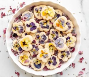 Edible shortbread biscuits in a white bowl with edible flowers on top
