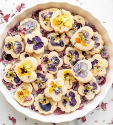 Edible shortbread biscuits in a white bowl with edible flowers on top