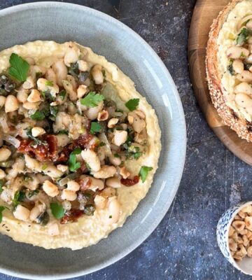 A bowl of Mediterranean beans on toast served with crusty bread and houmous