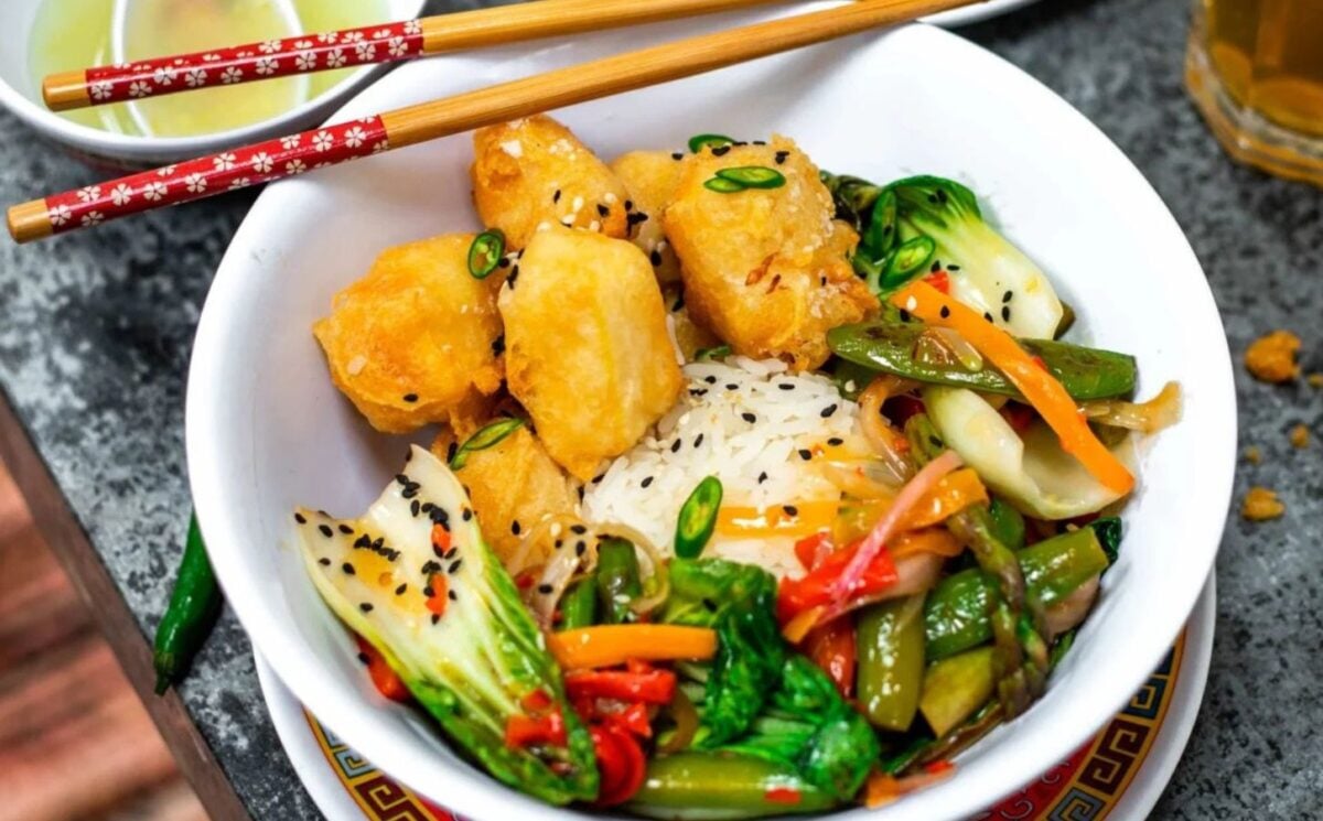Photo shows a bowl of crispy lemon tofu, cooked with veggies and served with white rice