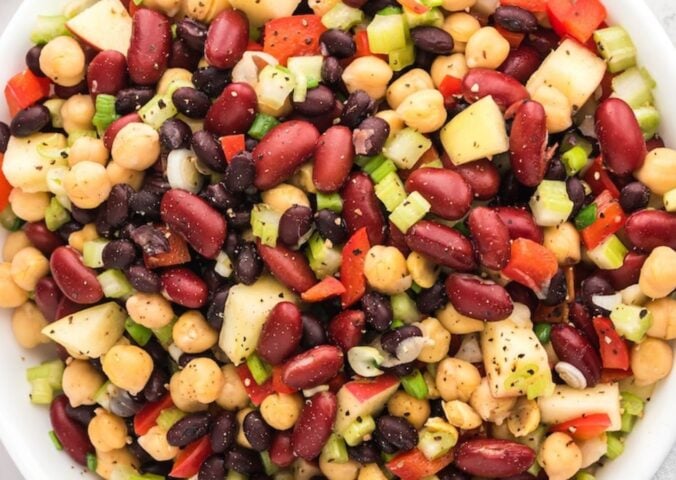 three bean salad made with chickpeas, kidney beans, black beans, apple pieces, and a tangy vinegar dressing