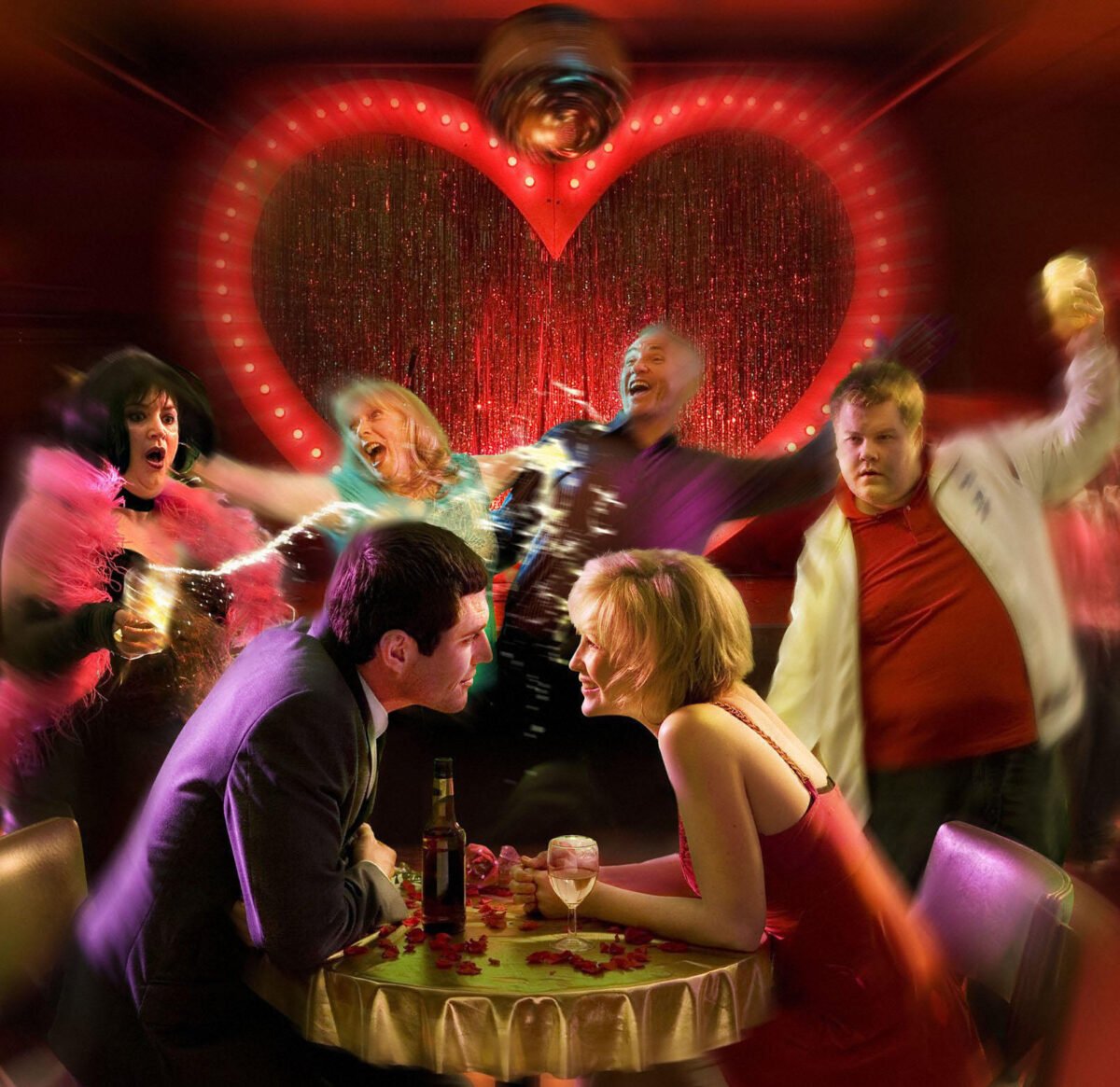 The cast of Gavin and Stacey standing in front of a large love heart on the wall of a restaurant