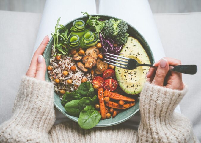 woman holding bowl of plant-based food