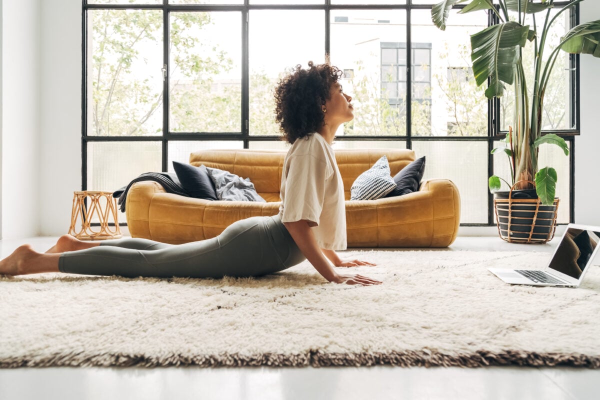 A woman doing yoga on a rug in a brightly lit lounge