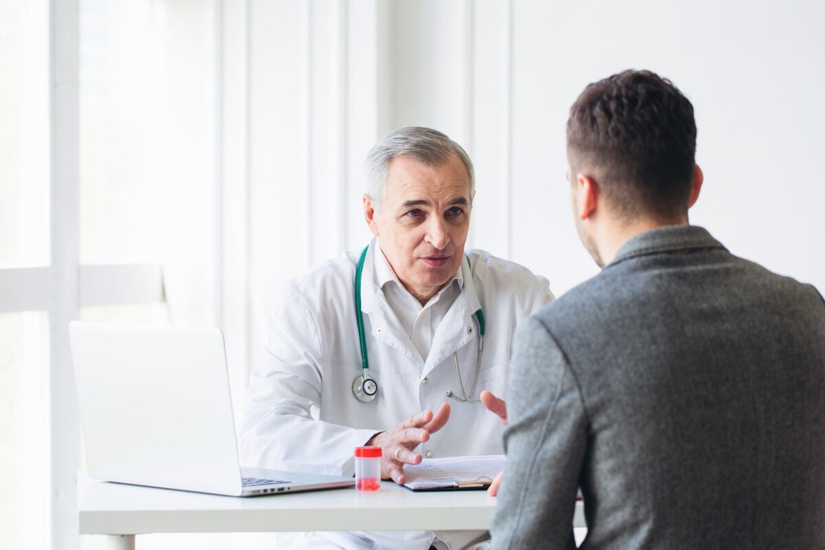 A man speaking to a doctor in a brightly lit room