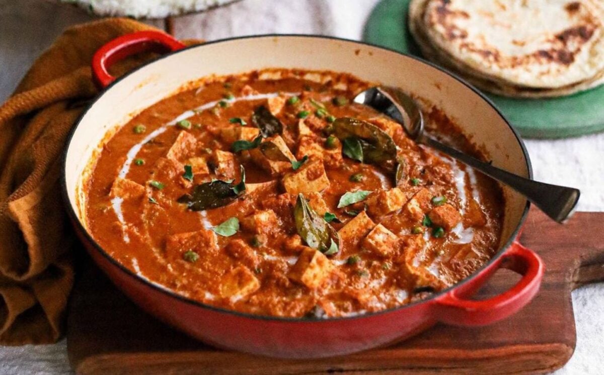 Photo shows a large red pot of vegan butter curry made with tofu