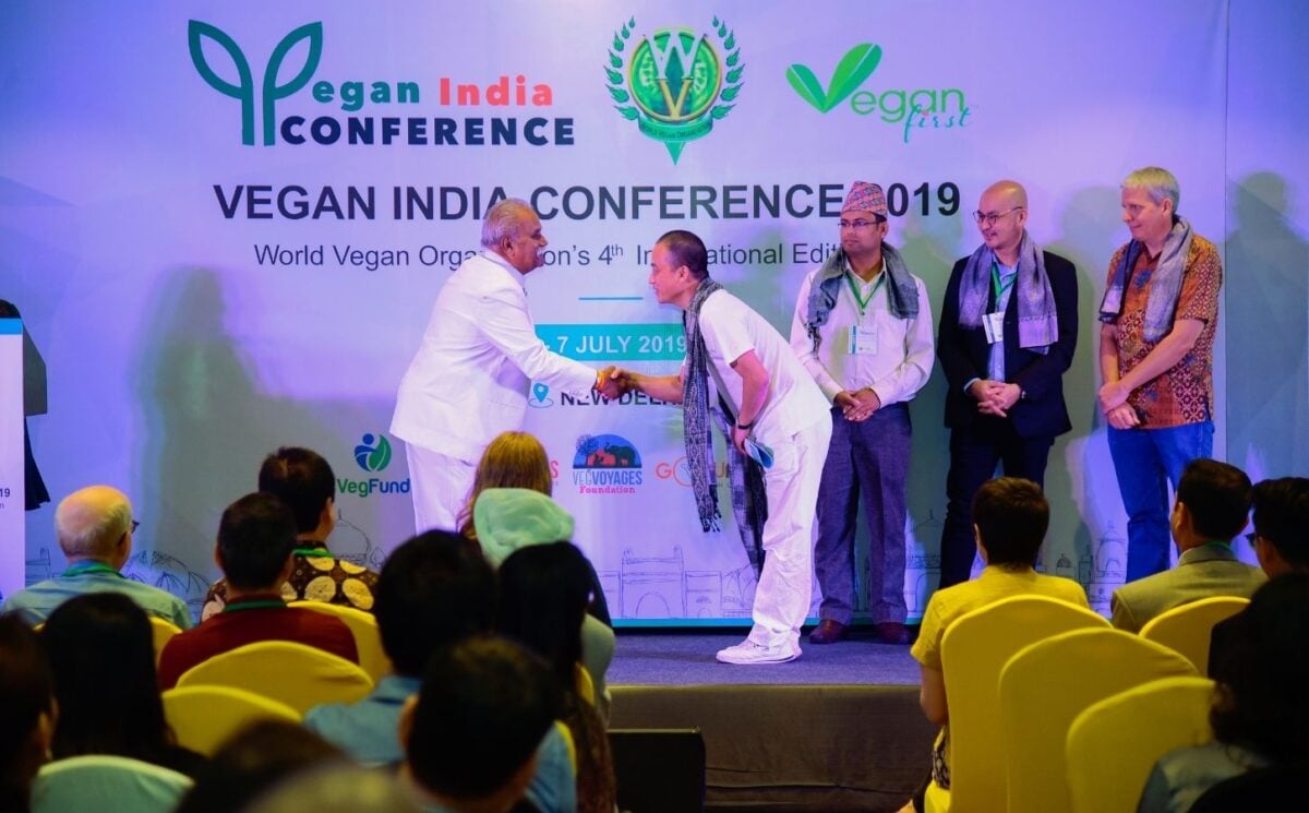 Two men shaking hands while on stage at the Vegan India Conference