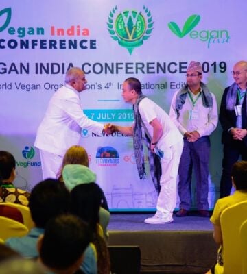 Two men shaking hands while on stage at the Vegan India Conference