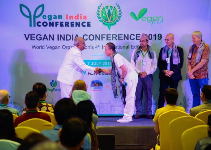 Two men shaking hands while on stage at the Vegan India Conference