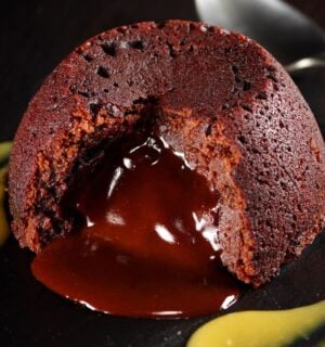a vegan chocolate fondant cake on a plate with mango coulis