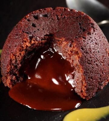 a vegan chocolate fondant cake on a plate with mango coulis