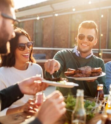 A group of friends sitting in the sun and eating meat