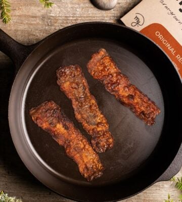 Photo shows the packaging of MyForest Foods Co's plant-based mycelium bacon as well as three slices browned in a cast iron pan