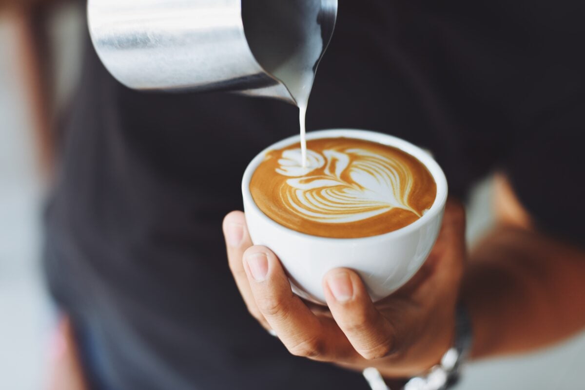 A barista making a latte in a coffee shop