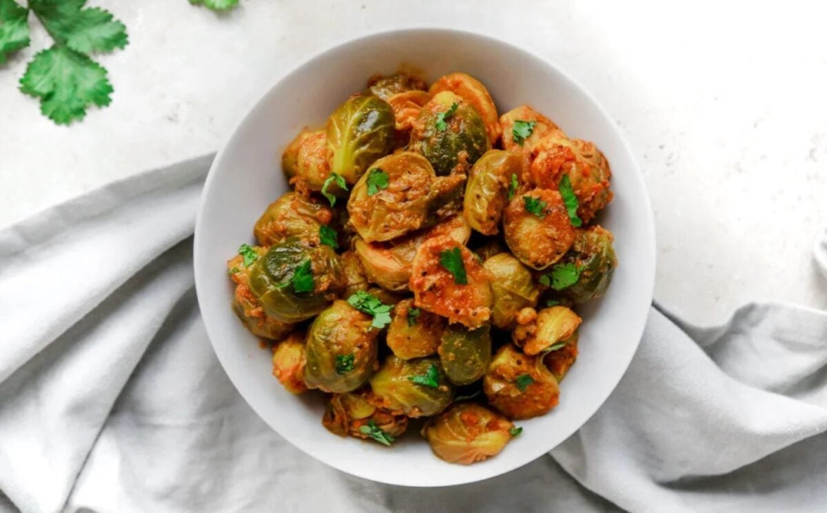 Photo shows a white bowl full of curried Brussels sprouts