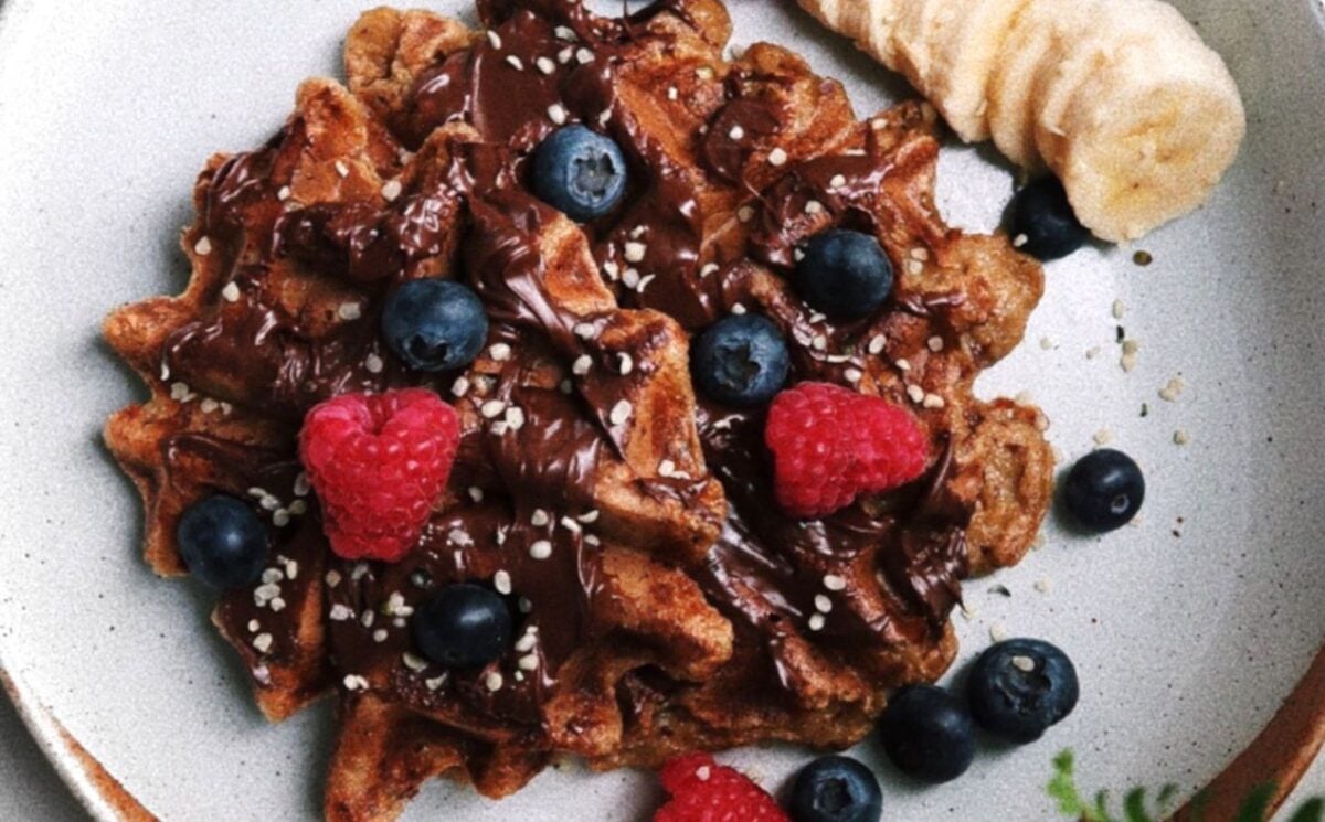 Photo shows an oat flour-based waffle topped with fruit and berries