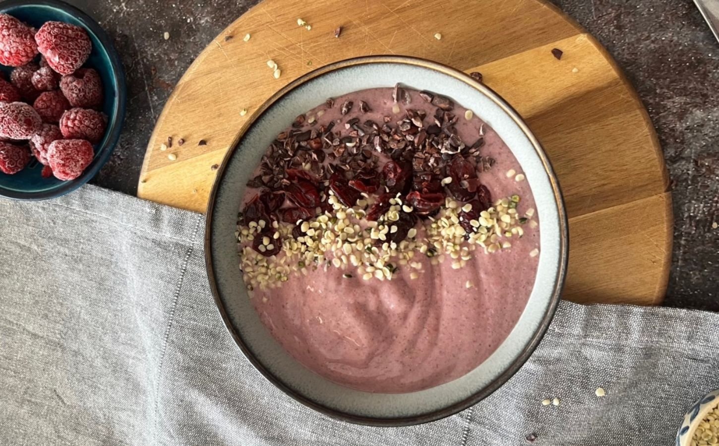 A picture of a vegan raspberry smoothie bowl topped with hemp hearts and cocoa nibs