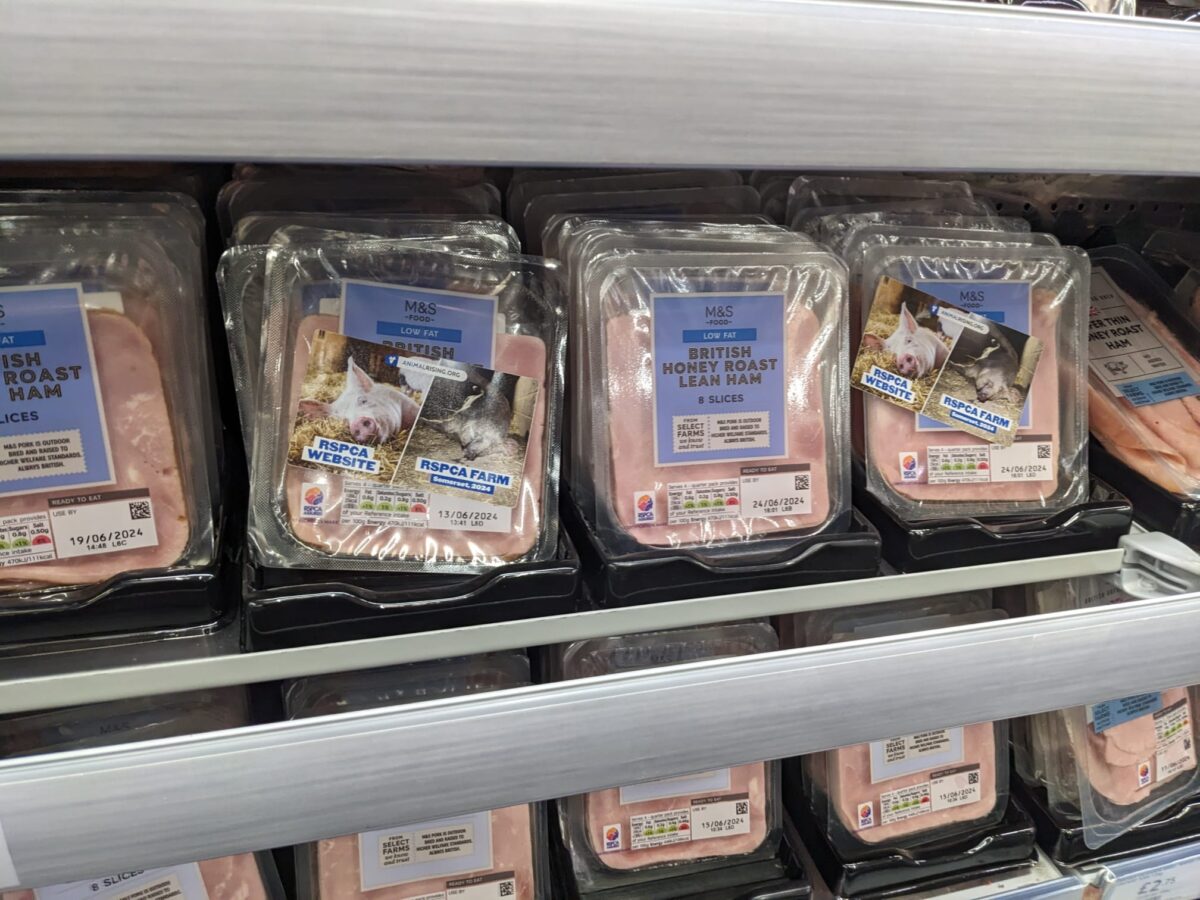 Packets of M&S RSPCA ham with stickers showing the reality of how pigs are treated on farms