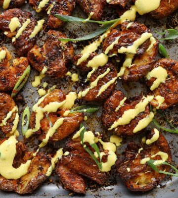 smashed new potatoes drizzled with a chili and turmeric vegan mayo dip, coated in seasonings and olive oil