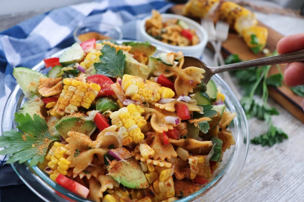 A colorful vegan southwest pasta salad full of corn on the cob, avocado, and other veggies