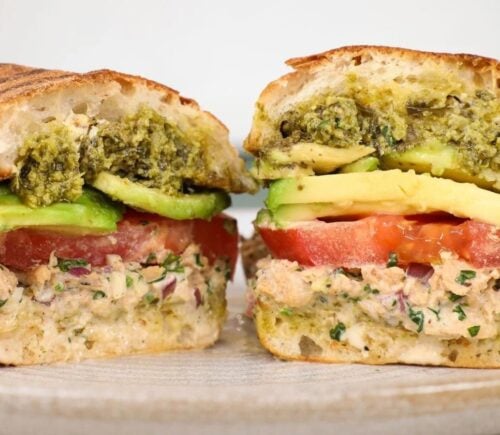 a vegan tunacado sandwich made with chickpea tuna, avocado, tomato, and pesto on a roll