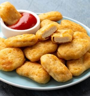 A plate full of vegan chicken nuggets with a pot of tomato ketchup